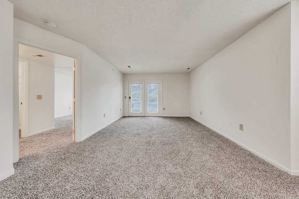 A spacious room with a carpeted floor and a door at the end at WaterFront Apartments, Virginia Beach, 23453