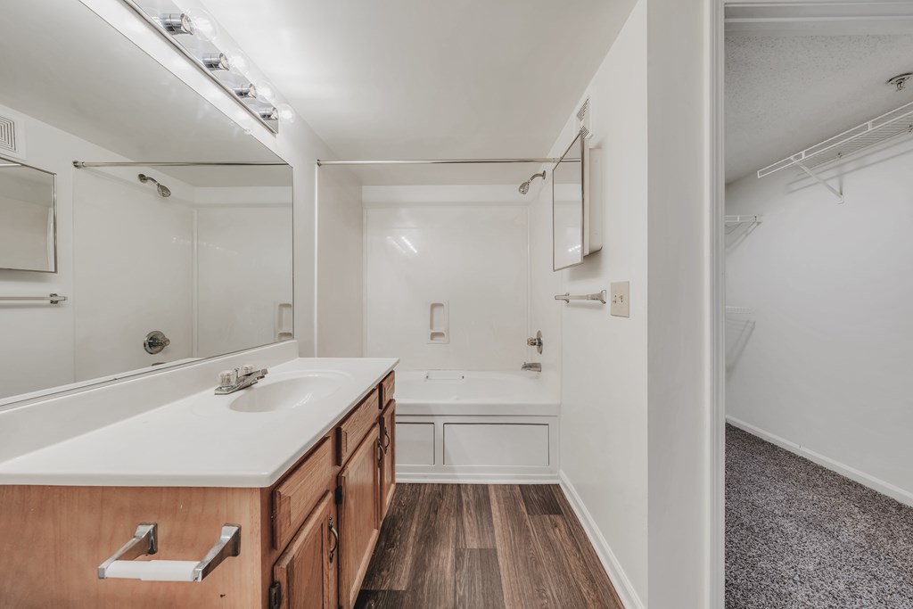 A bathroom with a wooden vanity and a white countertop at WaterFront Apartments, Virginia Beach, 23453