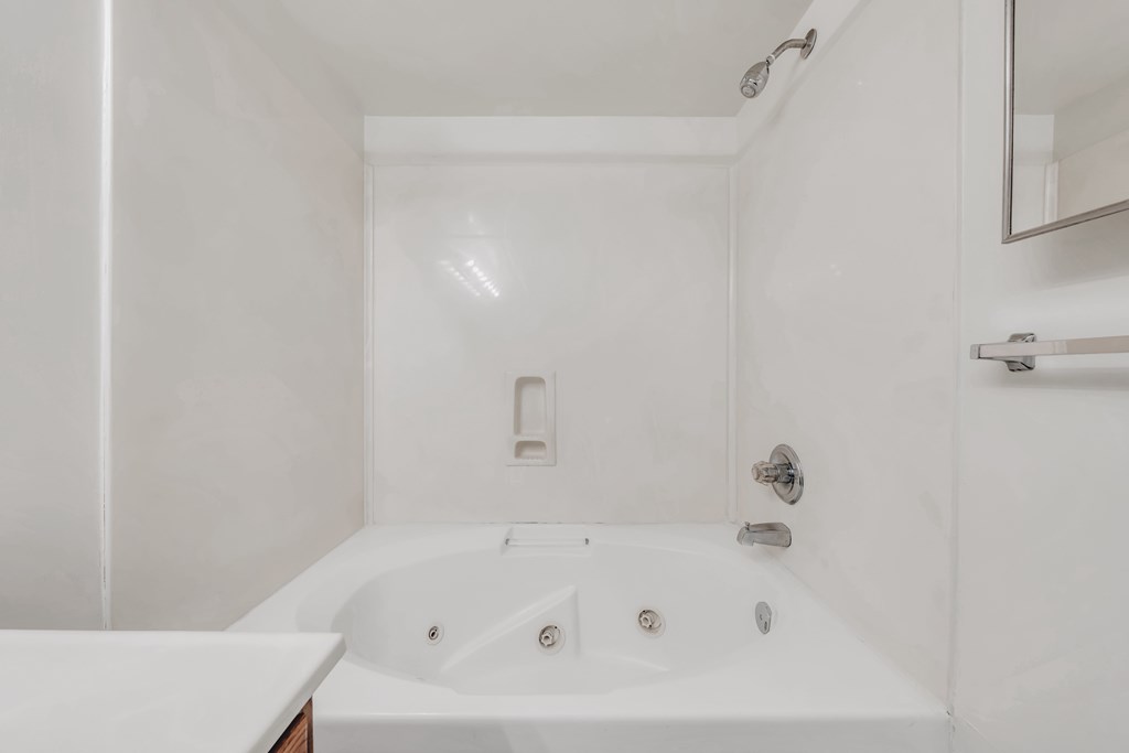A white bathroom with a tub and a mirror at WaterFront Apartments, Virginia Beach, 23453