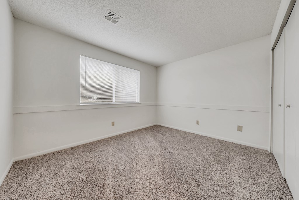 A room with a carpeted floor and a window with blinds at WaterFront Apartments, Virginia Beach, 23453