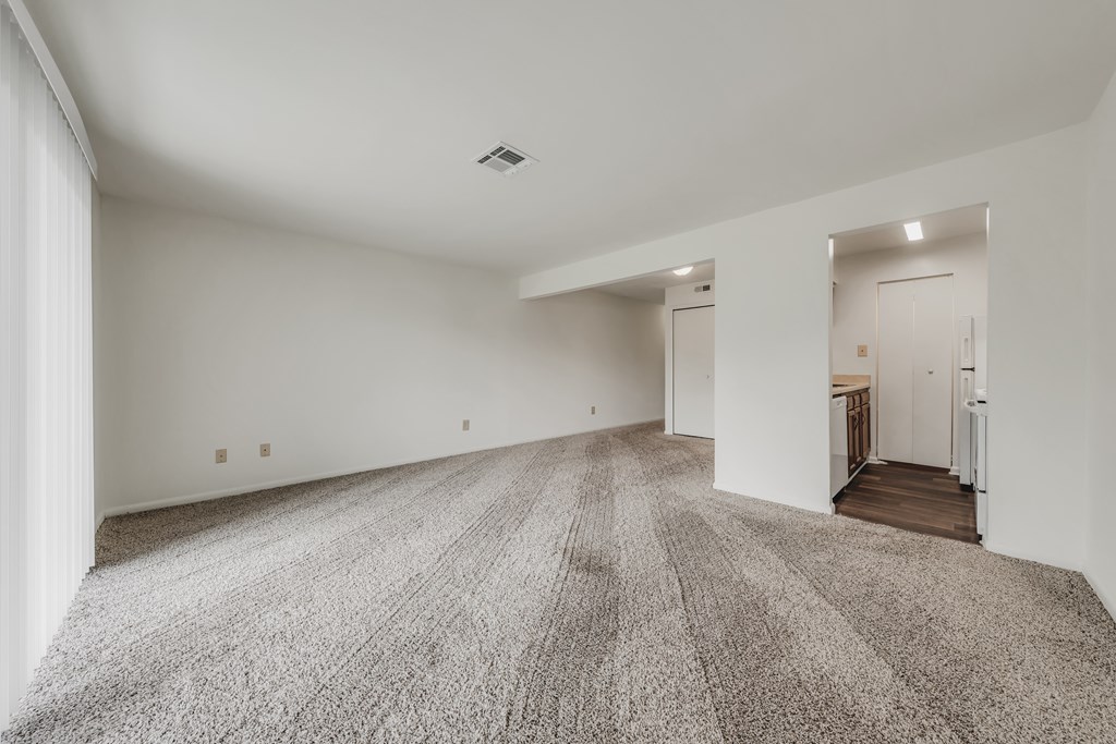 A large, empty room with a carpeted floor and white walls at WaterFront Apartments, Virginia Beach, 23453