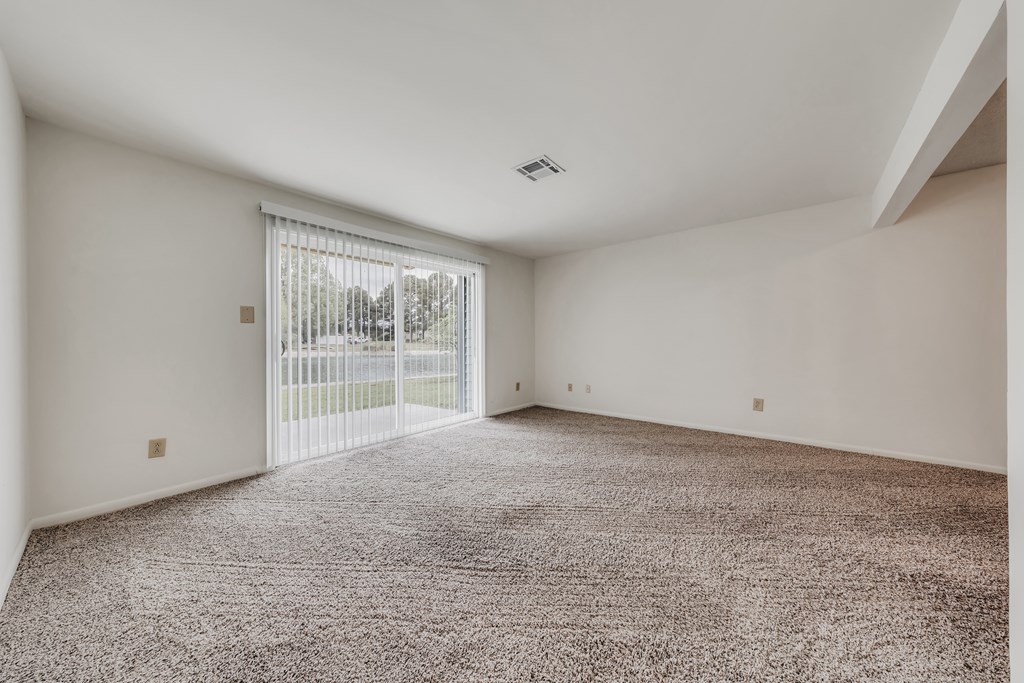 A room with a carpeted floor and a sliding glass door at WaterFront Apartments, Virginia Beach, 23453