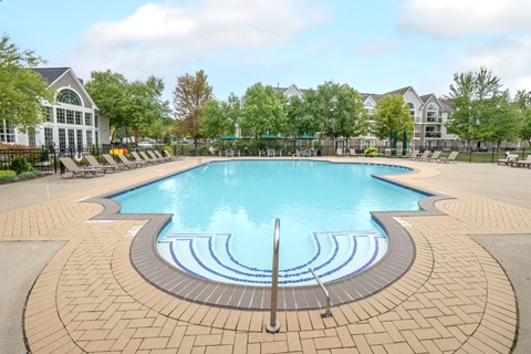 A large swimming pool surrounded by a brick patio.