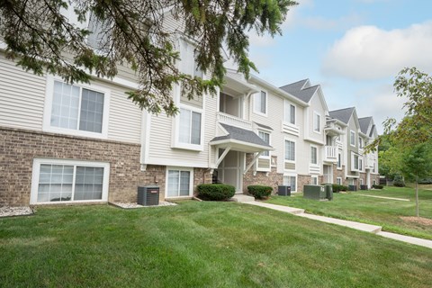 A row of townhouses with green lawns in front.