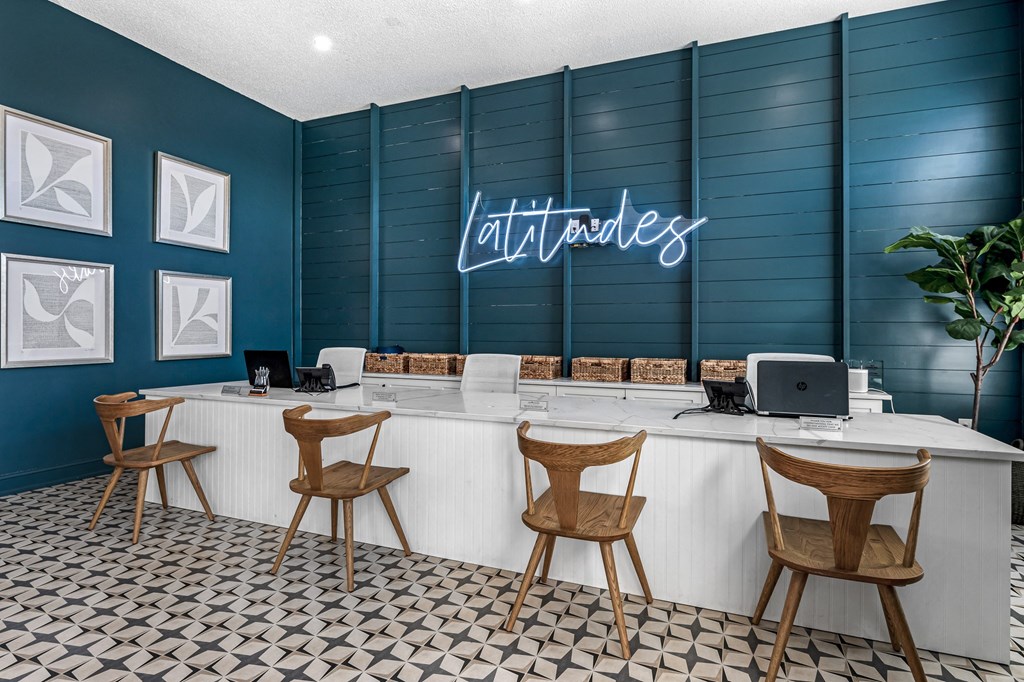 a blue and white lobby with chairs and a desk with a laptop at Latitudes Apartments, Indianapolis, IN