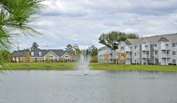 a fountain in the middle of a lake with apartment buildings in the background