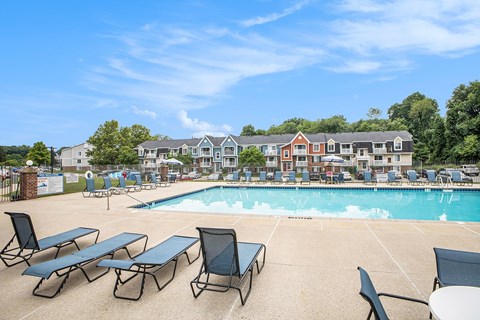 A pool with sun loungers and an apartment building in the background at Apple Ridge Apartments, Michigan, 49534