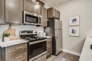 a kitchen with stainless steel appliances and wooden cabinets at 24 at Bloomfield, Bloomfield Township, MI