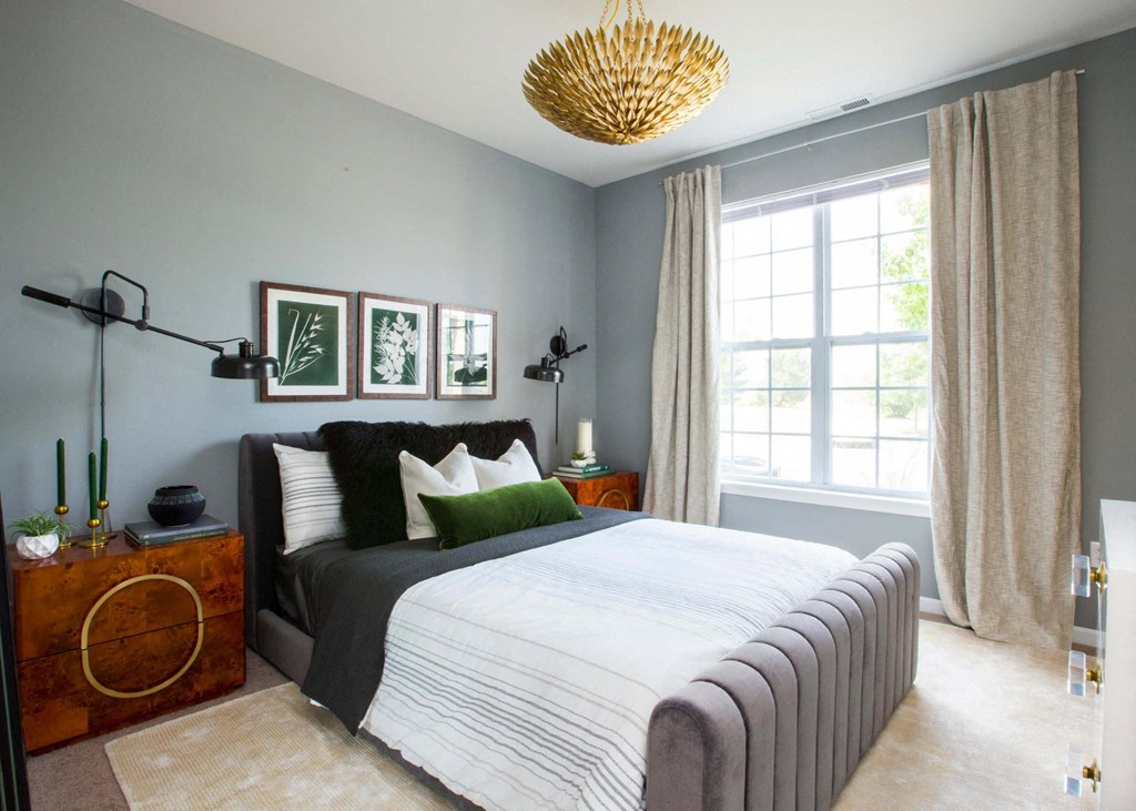 a bedroom with gray walls and a bed with a white comforter and green pillows  at Brickshire Apartments, Merrillville