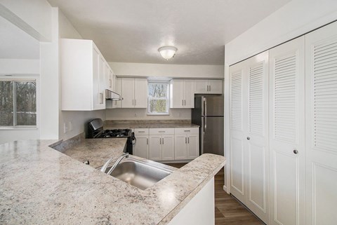 A kitchen with white cabinets and a breakfast bar at Black Sand Apartment Homes in Lincoln, NE