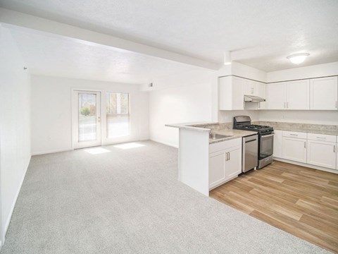 an upgraded kitchen and living room with white cabinets at Black Sand Apartment Homes in Lincoln, NE