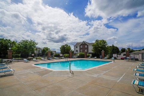 a swimming pool with chairs around it and a building in the background