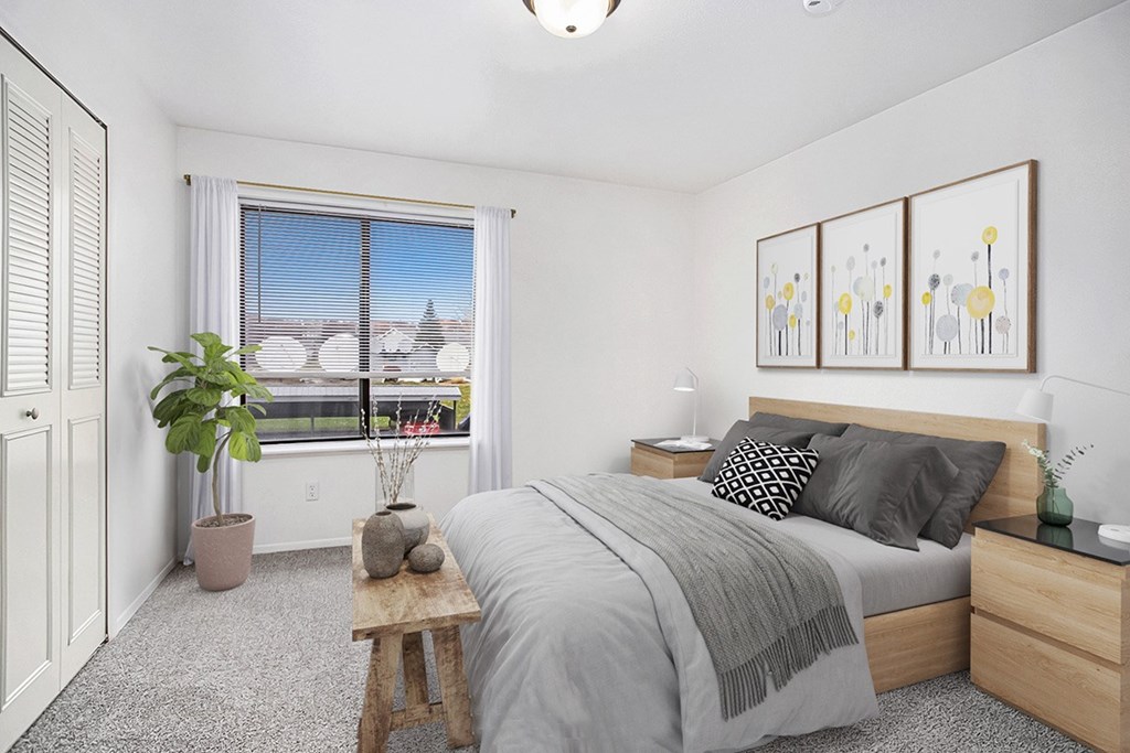 A bedroom with a large bed, a window, and a potted plant at Brentwood Park Apartments in LaVista, NE