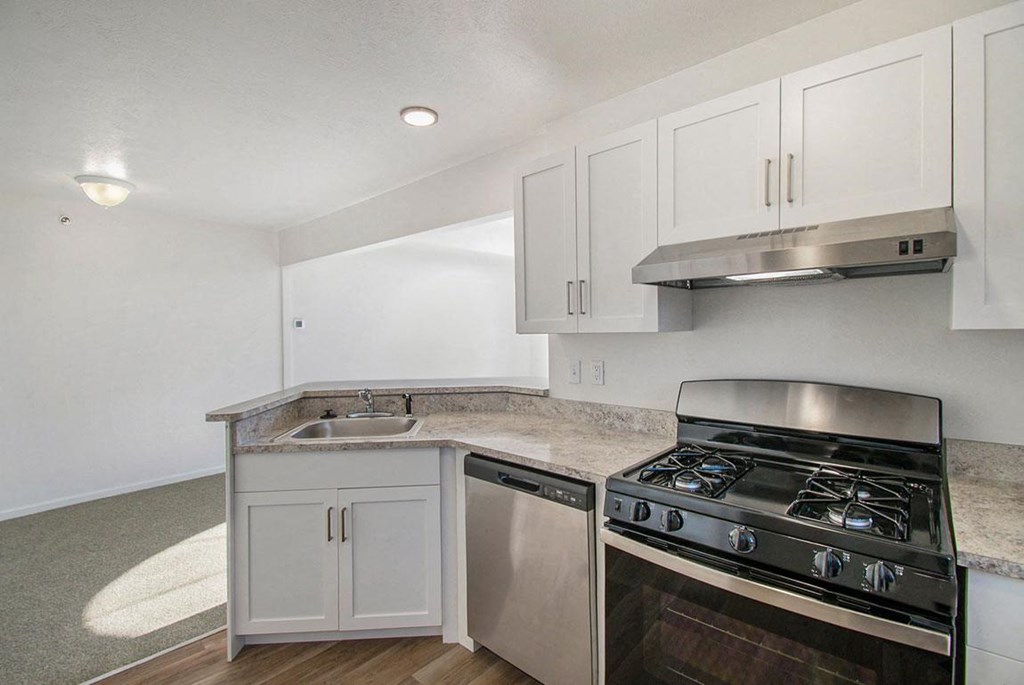 A kitchen with a gas stove, dishwasher, and white cabinets at Brentwood Park Apartments, La Vista, Nebraska