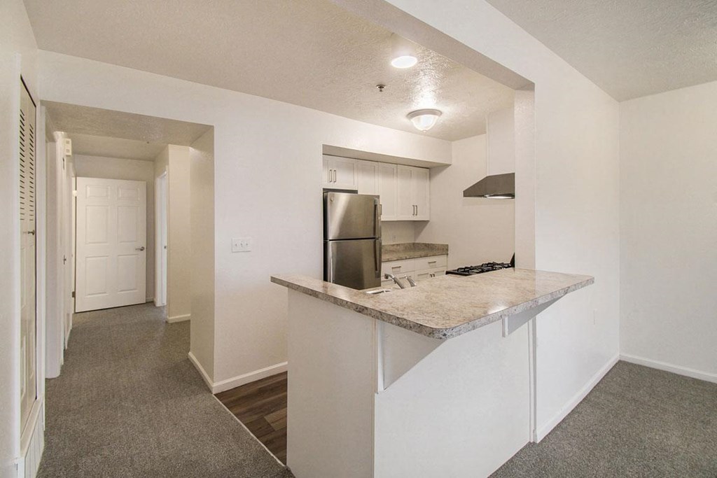 A kitchen with a breakfast bar and a stainless steel refrigerator at Brentwood Park Apartments, La Vista, Nebraska