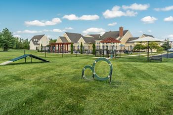 A playground with a green swing set and a large metal ring in the foreground