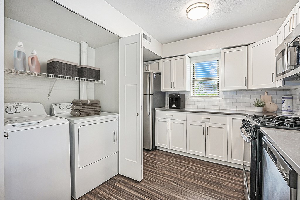 A white kitchen with hard surface floors and a washer and dryer at Byron Lakes Apartments in Byron Center, MI