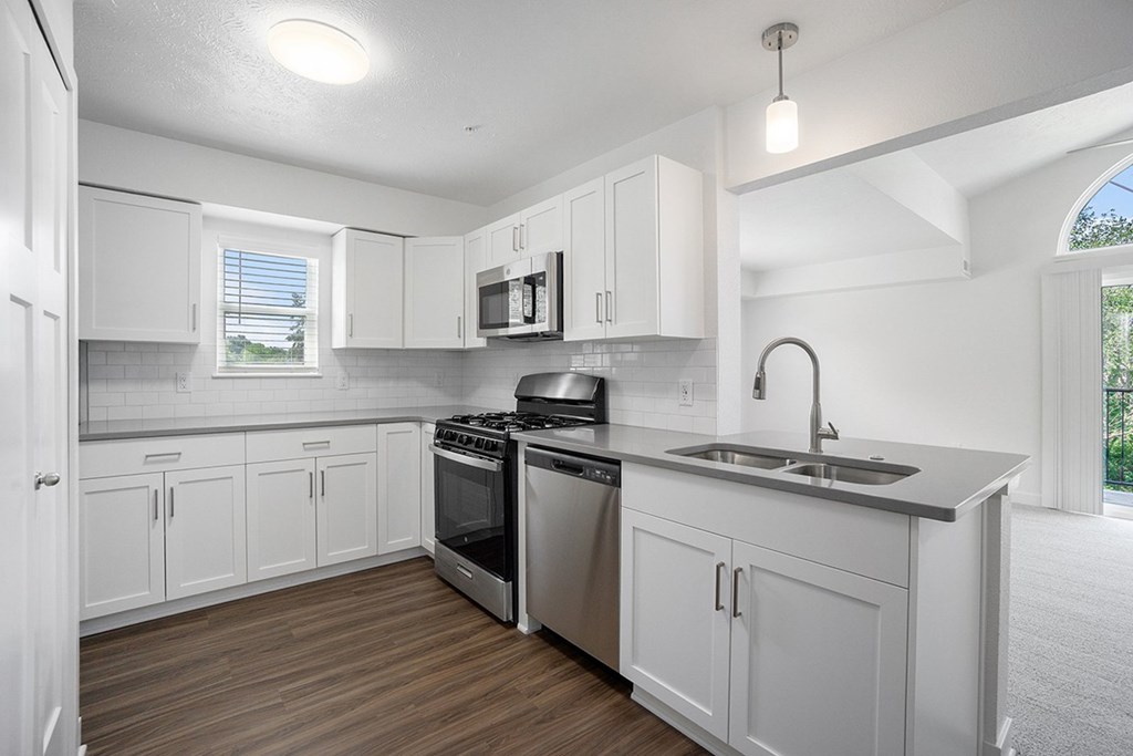 an empty kitchen with white cabinets and a sink  at Byron Lakes Apartments, Michigan, 49315
