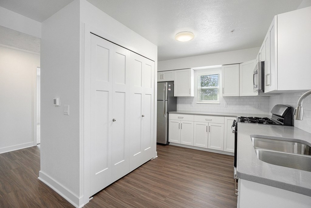 A kitchen with a window, white cabinets and a hard-surface floor at Byron Lakes Apartments, Byron Center, Michigan