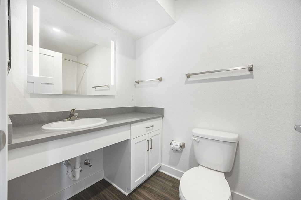 A bathroom with a sink and large mirror at Byron Lakes Apartments, Byron Center, MI