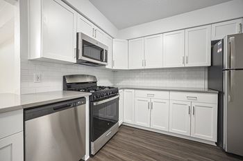 A kitchen with white cabinets and stainless steel appliances at Byron Lakes Apartments in Byron Center, MI