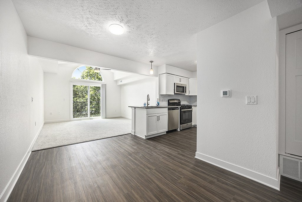 A kitchen and living room with a cathedral ceiling and a window to a balcony at Byron Lakes Apartments, Byron Center, MI