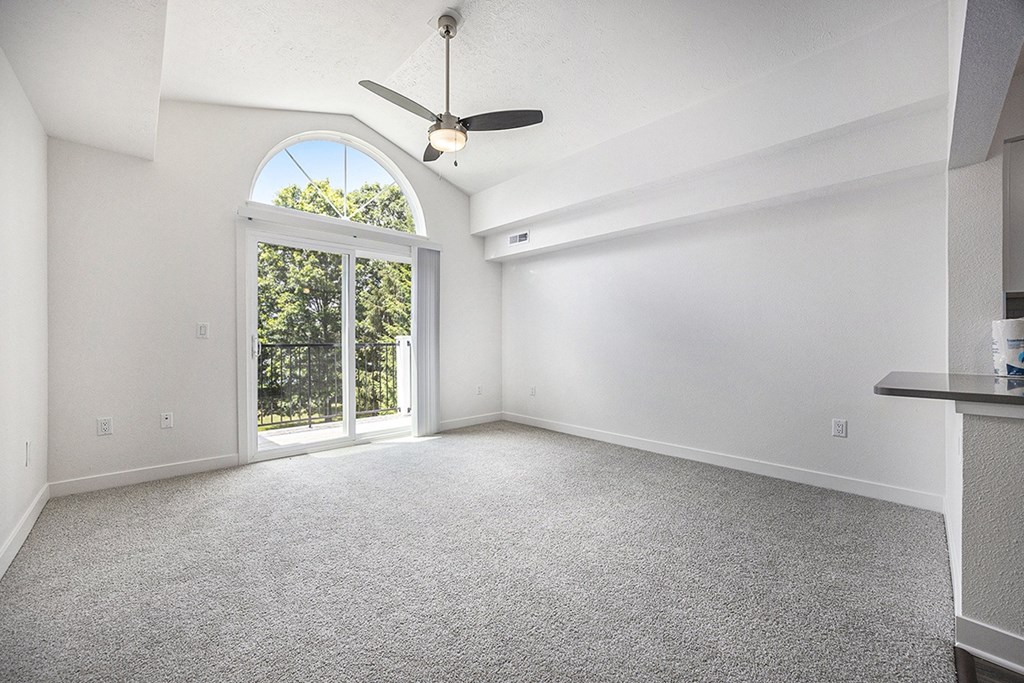 A living room with a ceiling fan and carpeted floor at Byron Lakes Apartments, Byron Center, MI