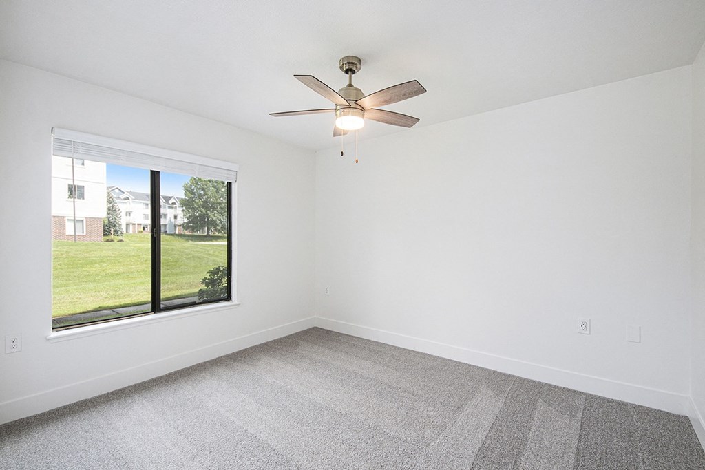A bedroom with a ceiling fan at Byron Lakes Apartments in Byron Center, MI