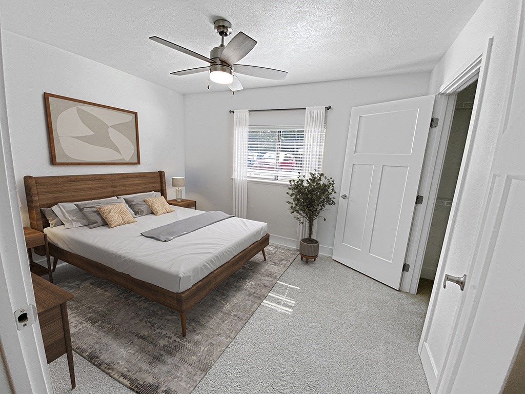 A bedroom with a bed, a ceiling fan, and a rug at Byron Lakes Apartments, Michigan, 49315