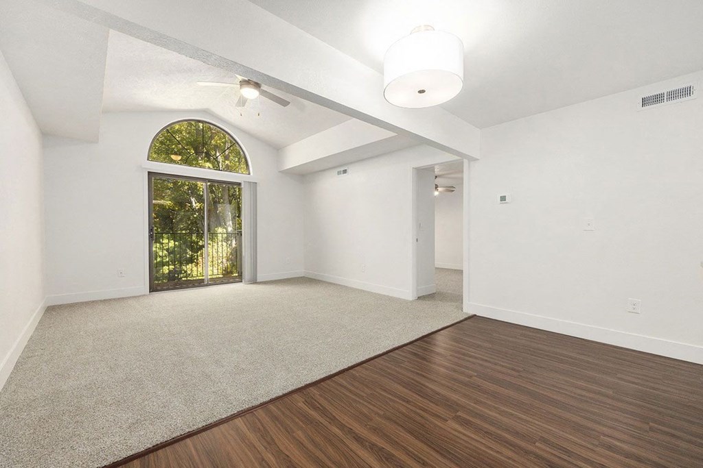 living room with cathedral ceiling and slider to private balcony at Byron Lakes Apartments, Byron Center, MI