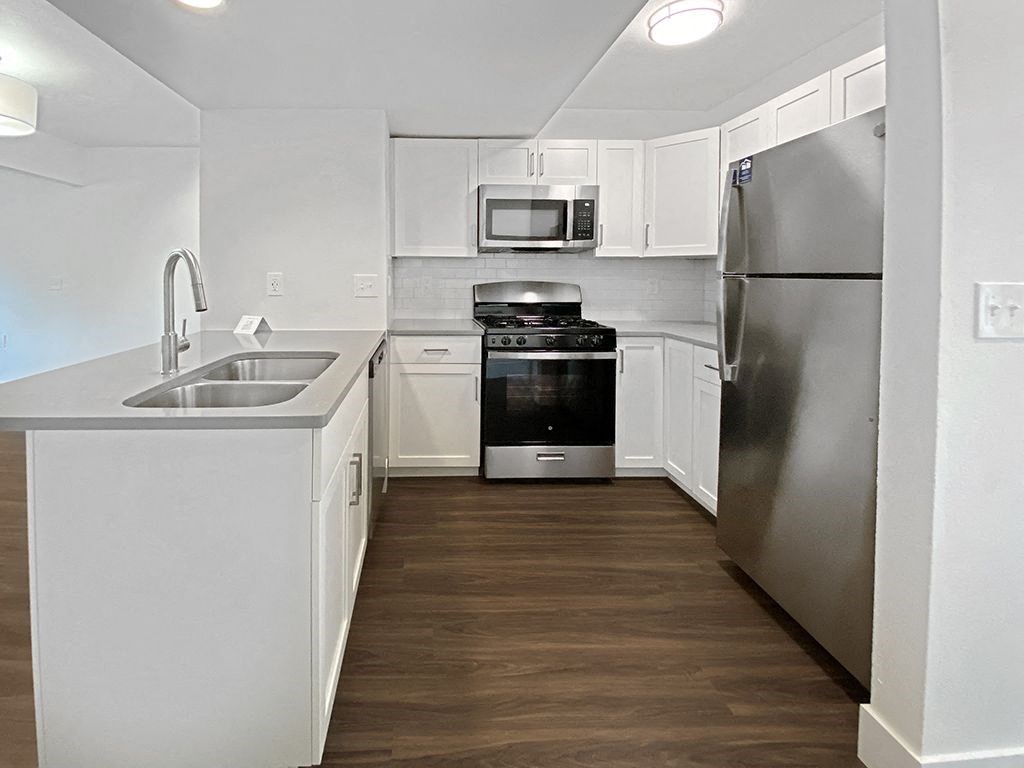 A kitchen with white cabinets and a fridge at Byron Lakes Apartments in Byron Center, MI