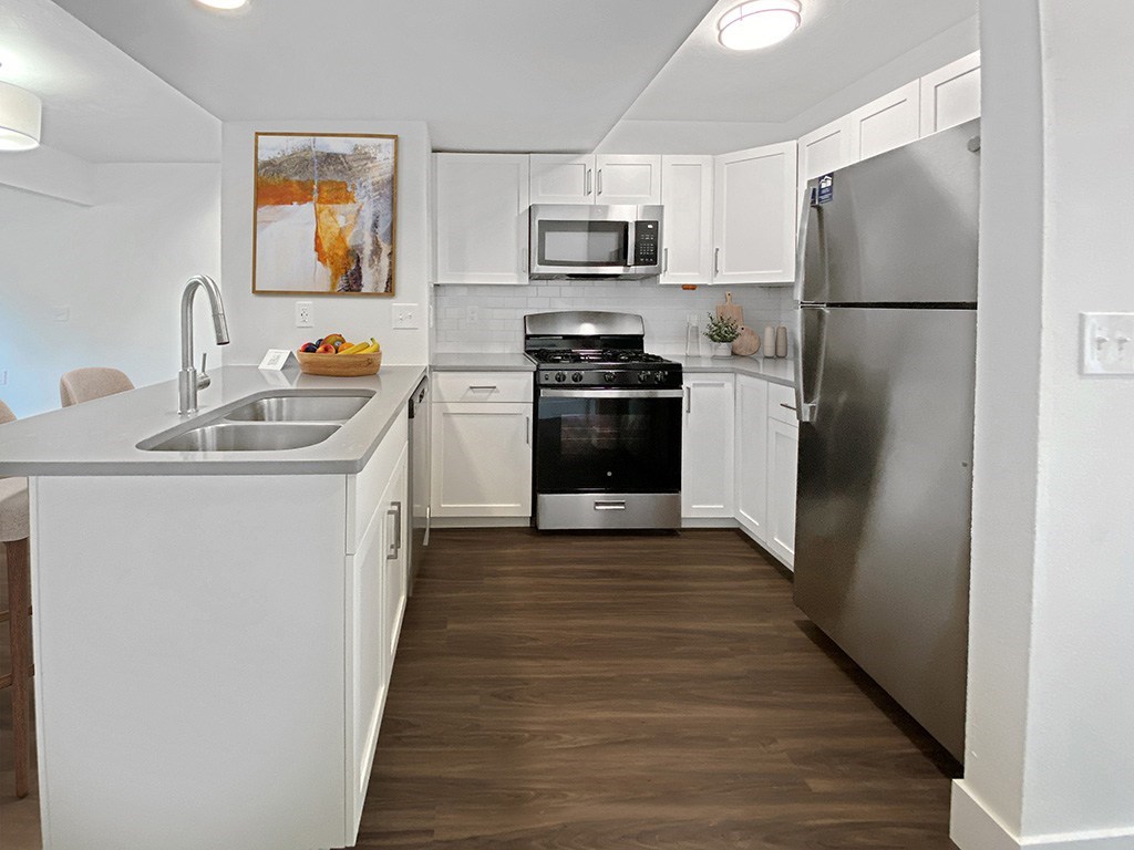 a kitchen with stainless steel appliances and white cabinets at Byron Lakes Apartments in Byron Center, MI