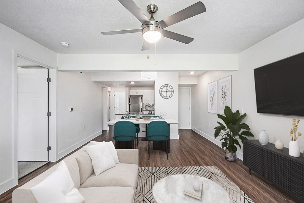 A living room with a white couch and a ceiling fan at Byron Lakes Apartments in Byron Center, MI