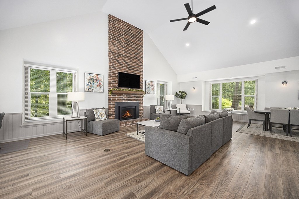 A community building with a fireplace and a grey couch at Byron Lakes Apartments, Byron Center, MI