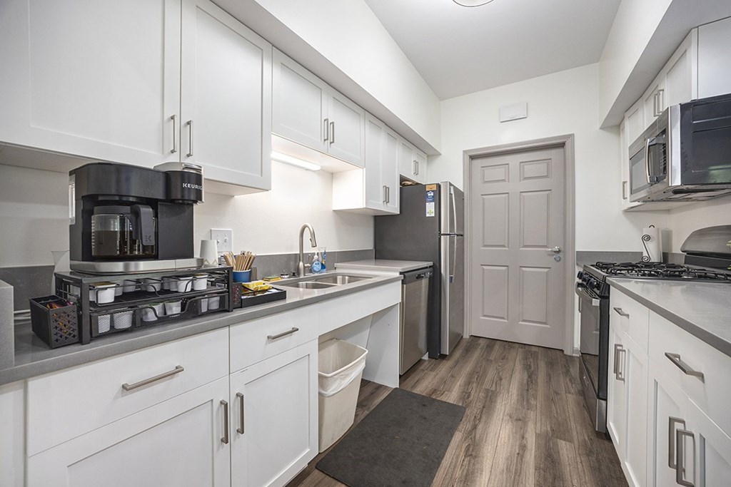 A clubhouse kitchen with white cabinets and stainless steel appliances at Byron Lakes Apartments, Byron Center, MI