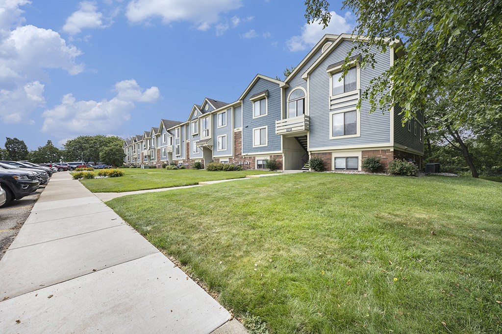 Exterior apartment building with a sidewalk in front at Byron Lakes Apartments, Byron Center, MI