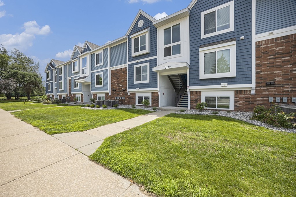 An apartment building with a sidewalk in front at Byron Lakes Apartments, Byron Center, MI