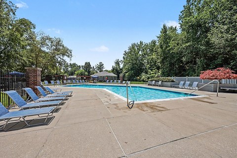 A pool surrounded by trees and chairs.