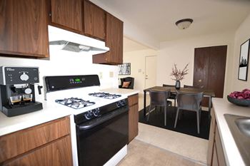 a kitchen with a stove top oven next to a table  at Fox Pointe Apartments, East Moline, IL