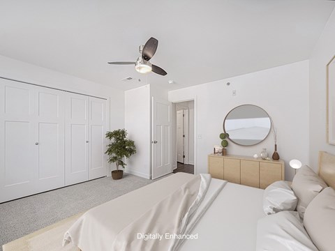 A bedroom with a bed, dresser, mirror, and a ceiling fan.