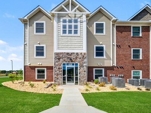 A modern two-story building with a stone entrance and a walkway leading to it.