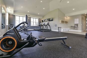 A gym with a row of treadmills and elliptical machines at Chase Creek Apartment Homes in Huntsville, AL 35811