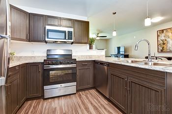 A kitchen with brown cabinets and a stainless steel refrigerator at Chase Creek Apartment Homes, Huntsville, AL, 35811