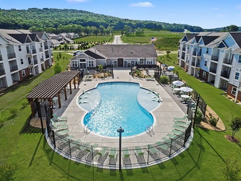 A large swimming pool surrounded by a black fence and a building in the background.