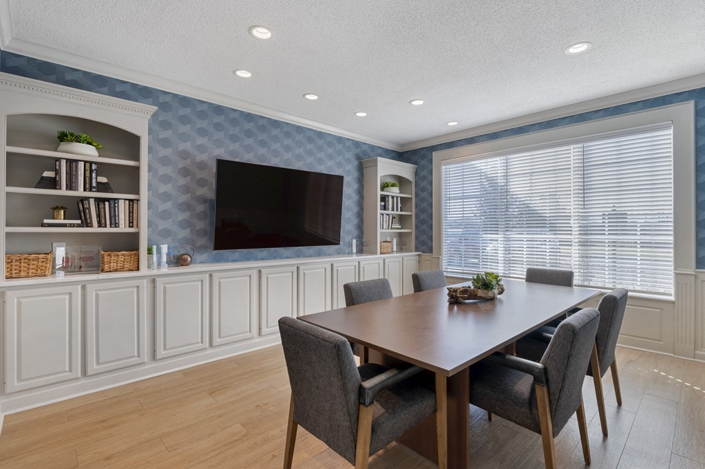 a dining room with a table and chairs and a tv on the wall at Latitudes Apartments, Indianapolis