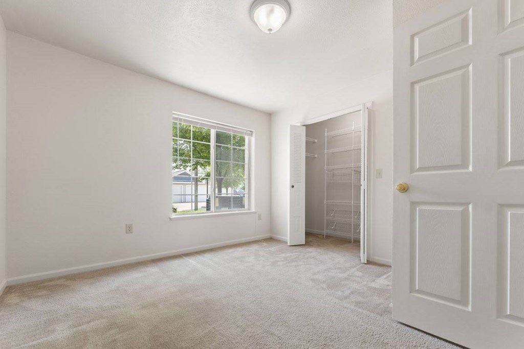 A bedroom with a large window and walk-in closet at Colonial Pointe at Fairview Apartments, Bellevue, 68123