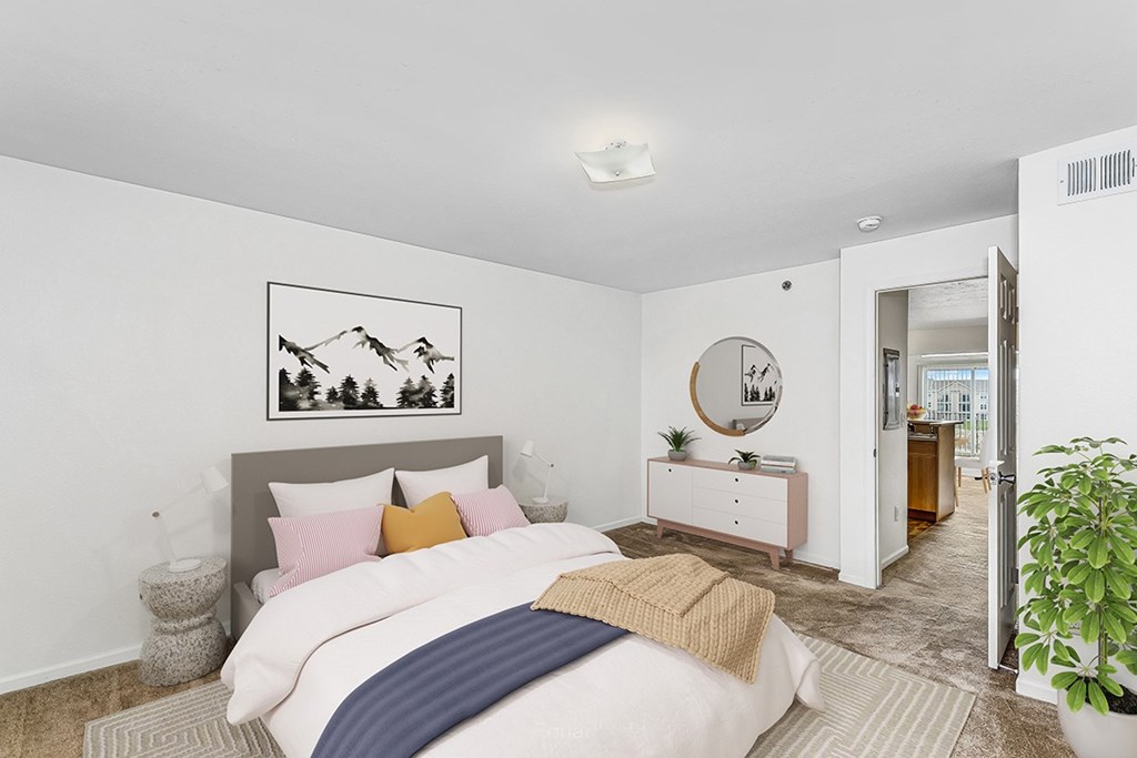 A bedroom with a bed, nightstand, and a painting on the wall at Colonial Pointe at Fairview Apartments, Bellevue, Nebraska