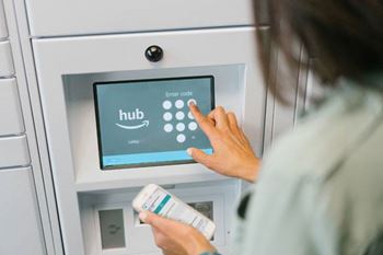 A person is interacting with a touchscreen device that has an Amazon Hub logo on it at Colonial Pointe at Fairview Apartments in Bellevue, NE