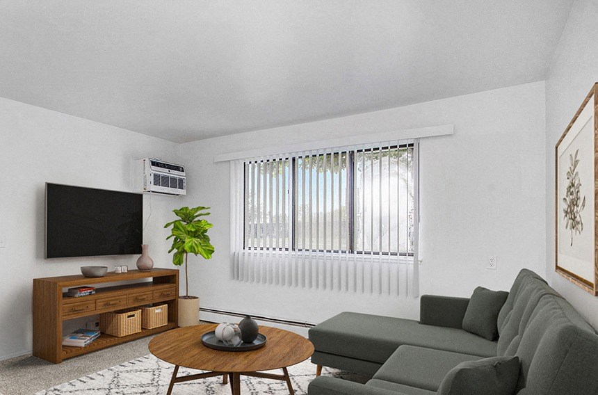A garden style living room with a grey couch, a coffee table, and a television at Concord Place Apartments in Kalamazoo, Michigan 49009