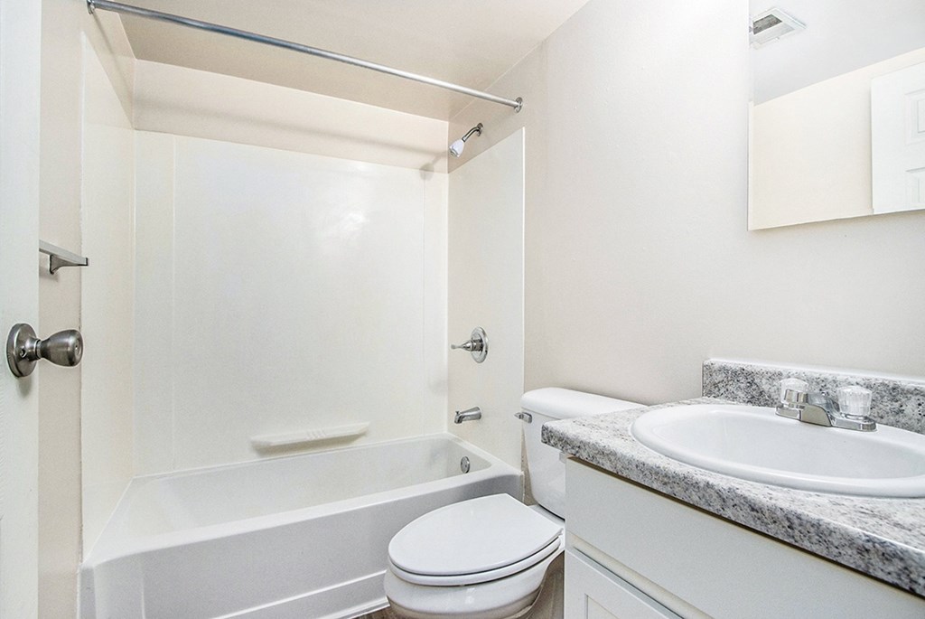 A white bathroom with a toilet, sink, and bathtub